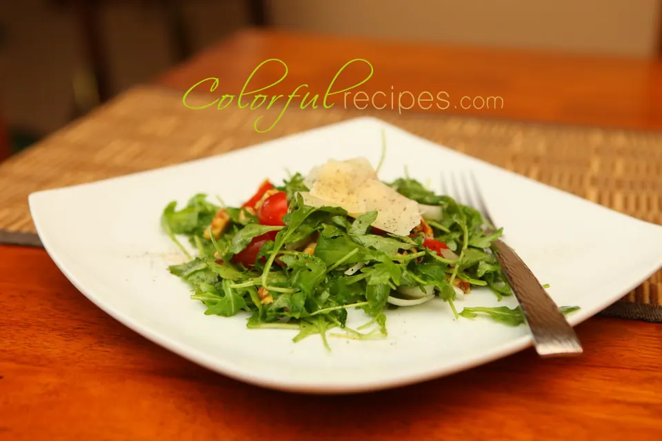 Plate of fresh arugula salad with cherry tomatoes and shaved Parmesan