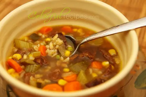 Bowl of vegetable beef barley soup with carrots, corn and celery