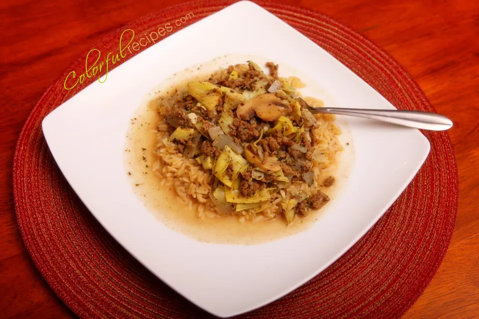 Plate of artichoke mushroom beef stew on brown rice with a red placemat