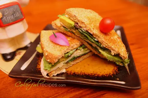 Turkey avocado sandwich on toasted whole grain bread with mixed greens