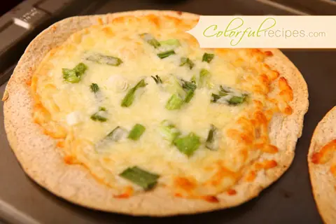 Baked cheese tortilla topped with melted mozzarella and chopped green onions