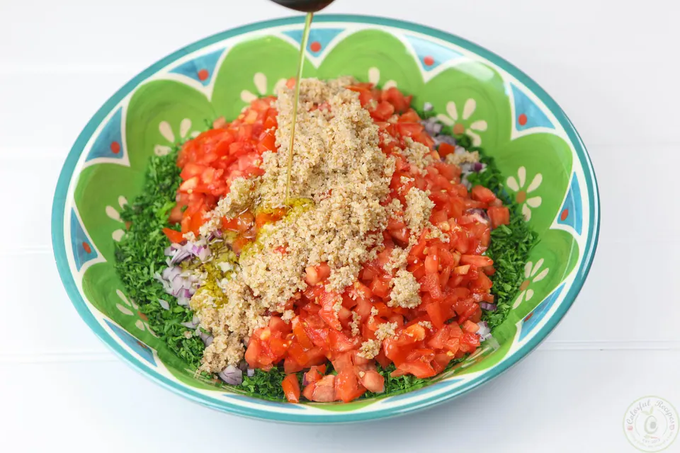 Chopped tomatoes and bulgur added to parsley for Lebanese tabbouleh