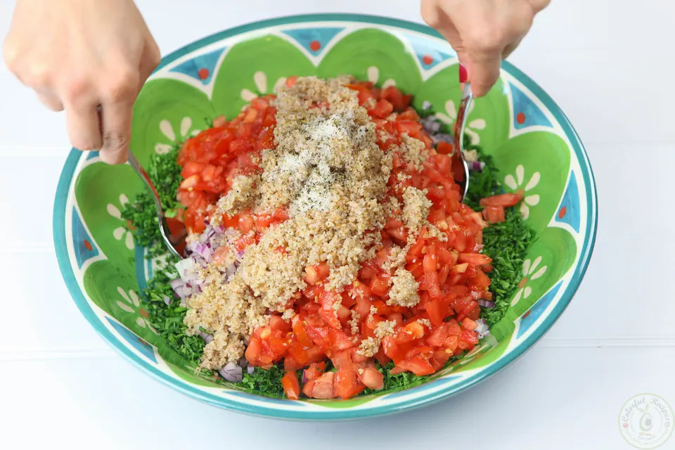 Mixing tomatoes and bulgur into the parsley for Lebanese tabbouleh