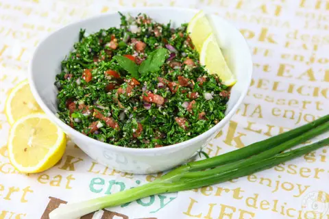 Bowl of authentic Lebanese tabbouleh with parsley, tomatoes and lemon wedges
