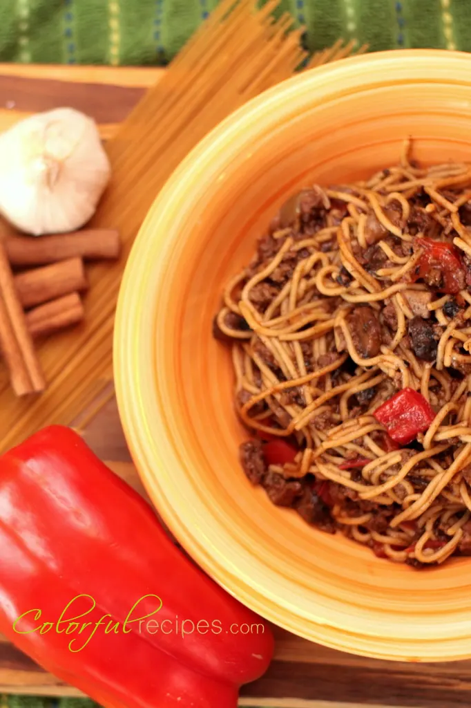 Bowl of mom's comfort spaghetti with red bell pepper, garlic and cinnamon sticks