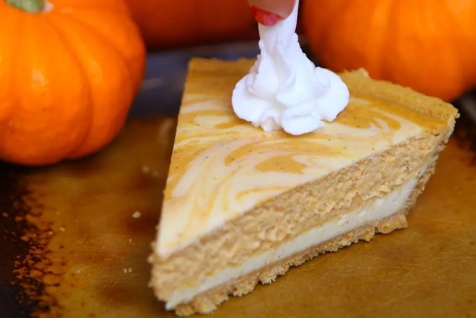Slice of cheesecake pumpkin swirl pie with a swirled cheesecake top
