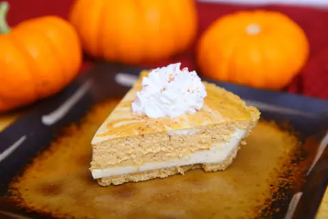 Slice of cheesecake pumpkin swirl pie in a graham cracker crust
