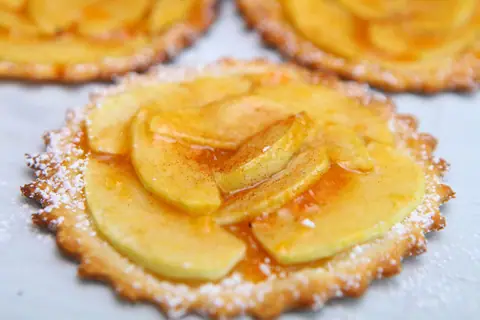 Mini French apple tart glazed with apricot jam and dusted with powdered sugar