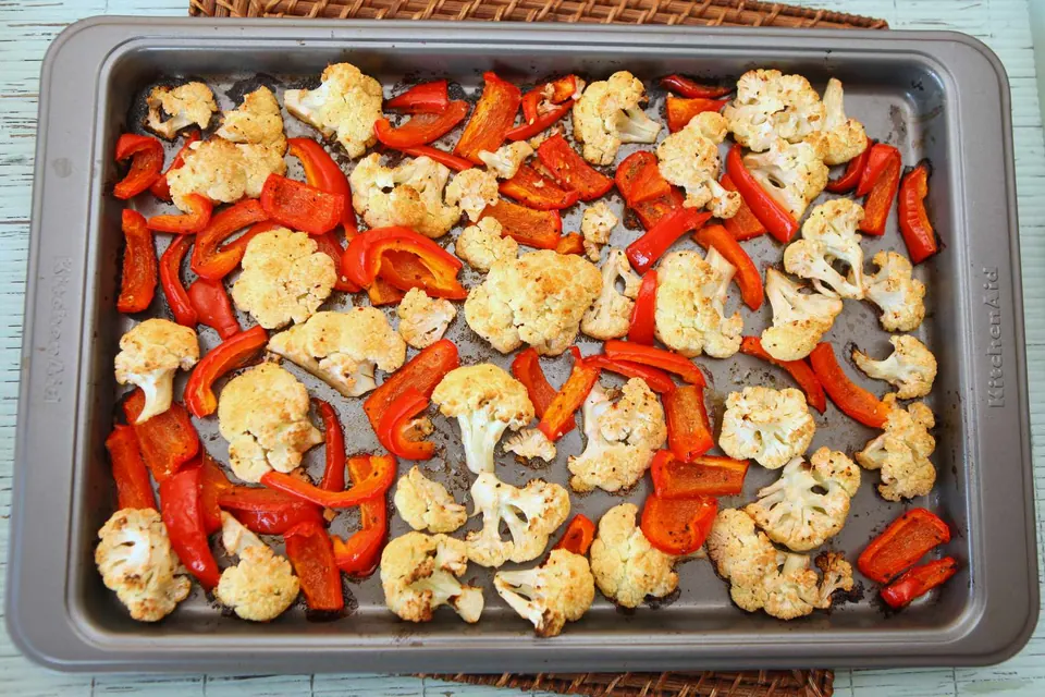 Roasted cauliflower and red peppers on a baking sheet
