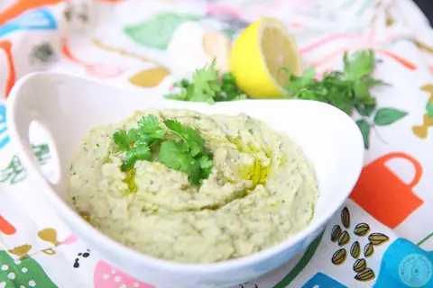 Bowl of cilantro white bean artichoke dip with lemon and fresh cilantro