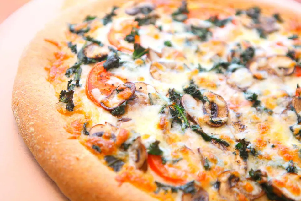 Close-up of flax whole wheat kale pizza with melted mozzarella, kale and mushrooms