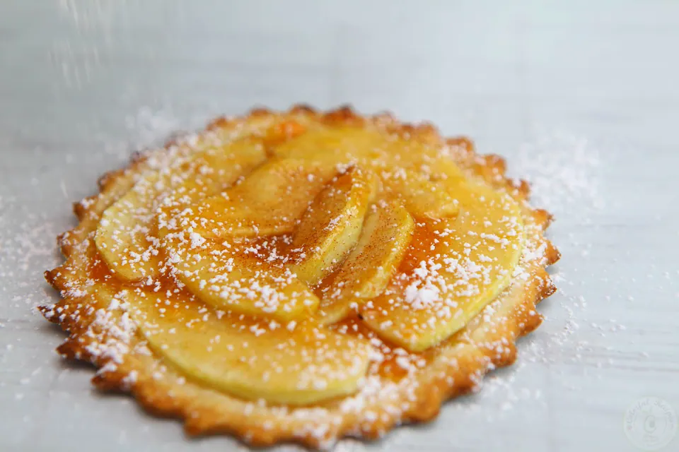 Mini French apple tart glazed with apricot jam and dusted with powdered sugar