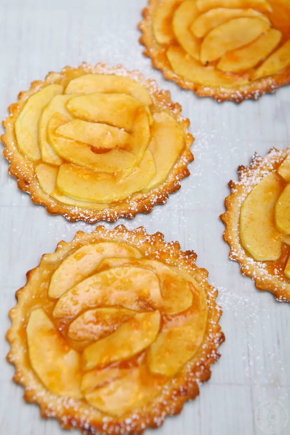Overhead view of baked mini French apple tarts on parchment
