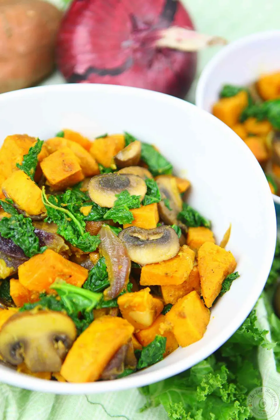 Spiced sweet potato kale mushroom sauté in a white bowl