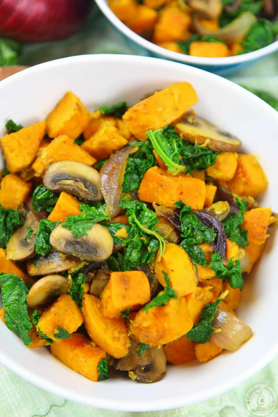 Bowl of spiced sweet potatoes with kale, mushrooms and red onion