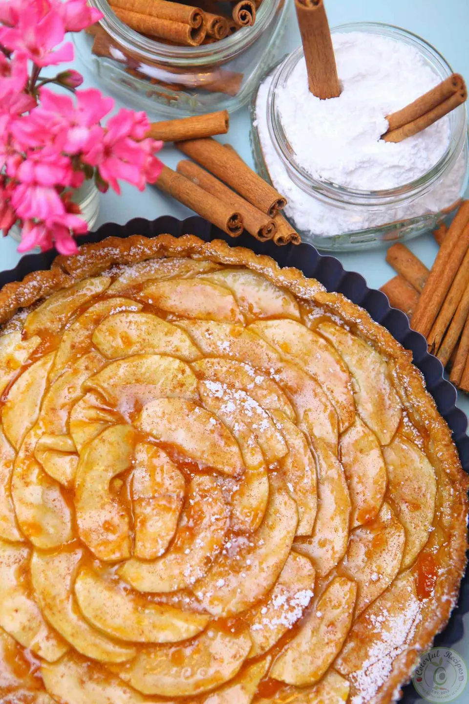 Easy French apple tart with thinly sliced apples arranged in a spiral next to cinnamon sticks
