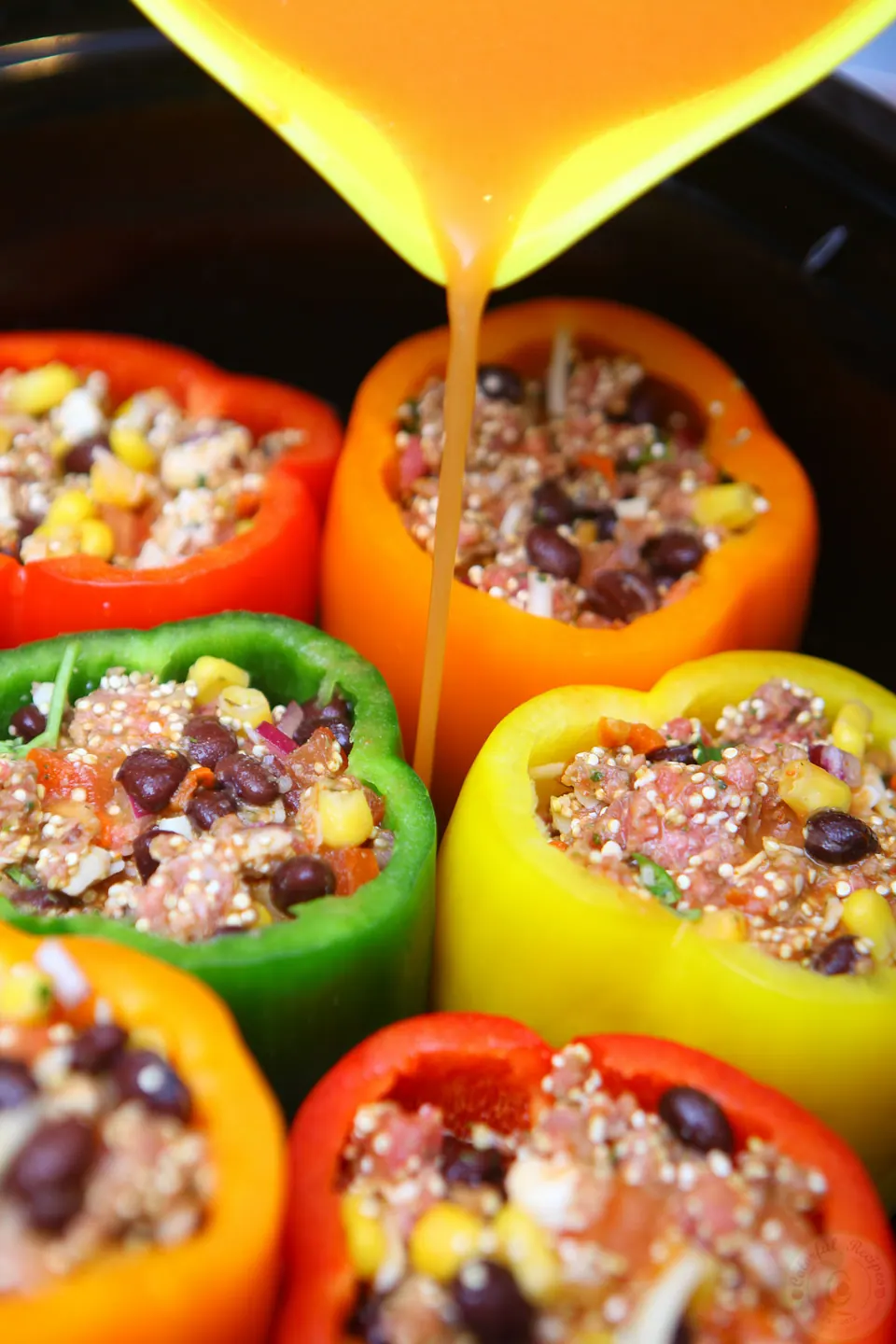 Pouring sauce over stuffed peppers in the crockpot