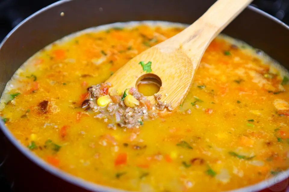 Taco filling simmering in broth in a deep pan