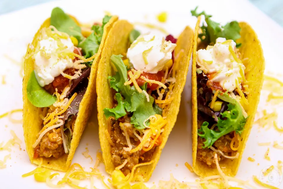 Three crunchy beef and quinoa tacos topped with lettuce, cheese and sour cream