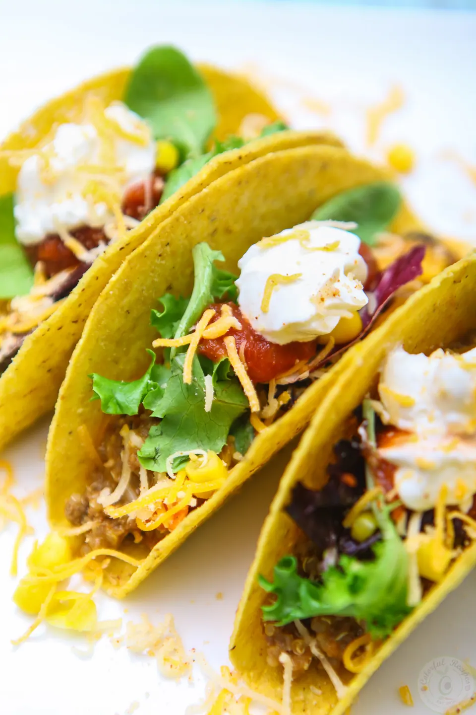 Beef and quinoa tacos topped with lettuce, shredded cheese and sour cream