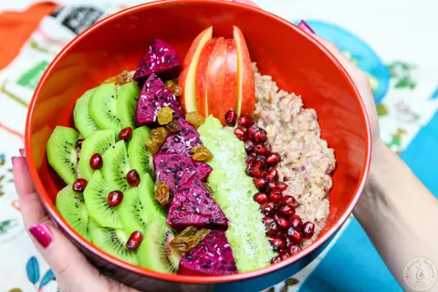 Exotic fruit oatmeal bowl with dragon fruit, kiwi, pomegranate and coconut flakes