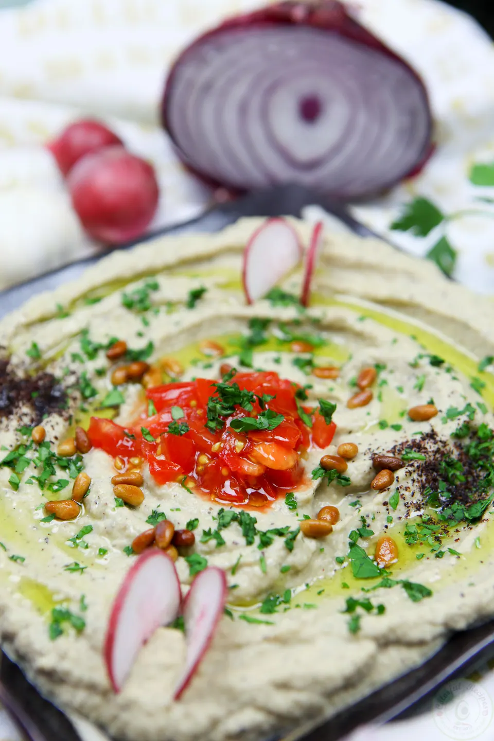 Lebanese baba ghanouj eggplant dip topped with tomatoes, parsley, pine nuts and radishes