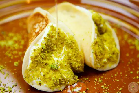 Simple ricotta stuffed atayef dipped in ground pistachios
