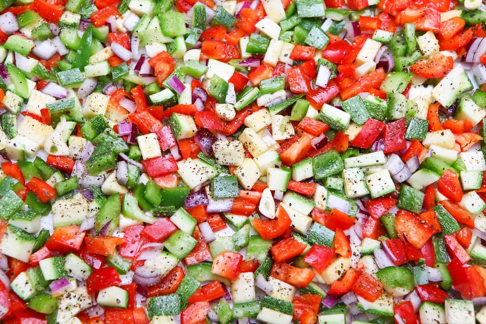 Diced peppers, zucchini, red onion and garlic spread out for roasted veggie quinoa pilaf