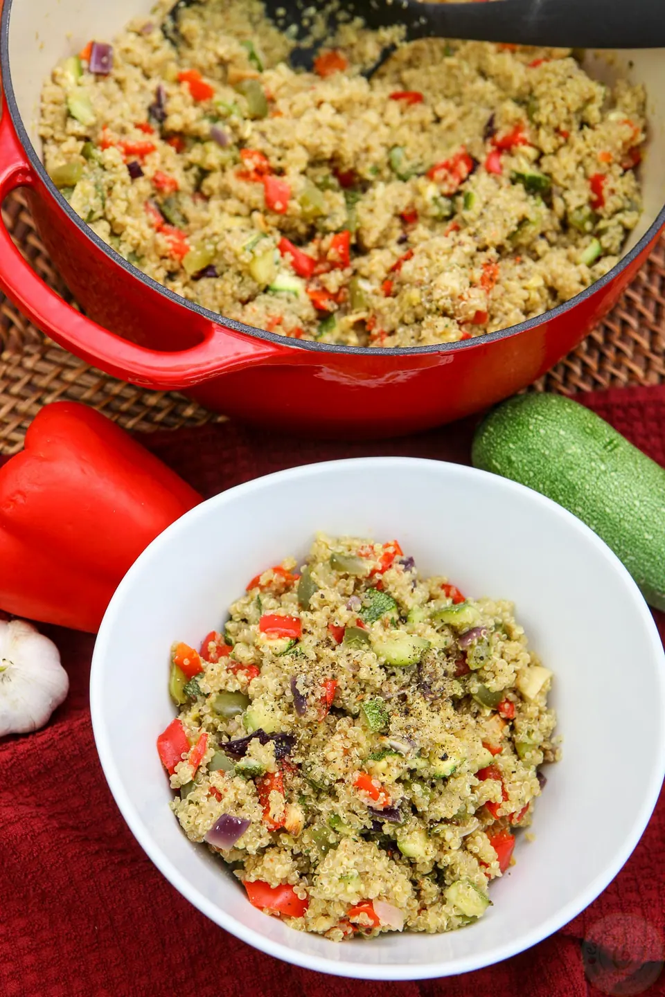 Roasted veggie quinoa pilaf in a red Dutch oven and a white serving bowl