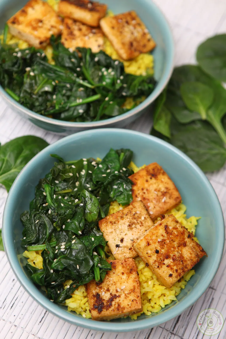 Bowl of simple spinach tofu with turmeric rice, wilted spinach and browned tofu
