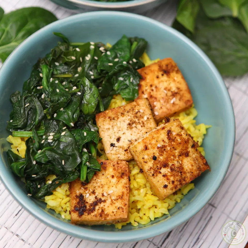 Close-up of golden tofu and wilted spinach over turmeric rice
