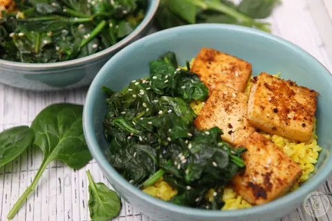 Bowl of simple spinach tofu with turmeric rice, wilted spinach and browned tofu