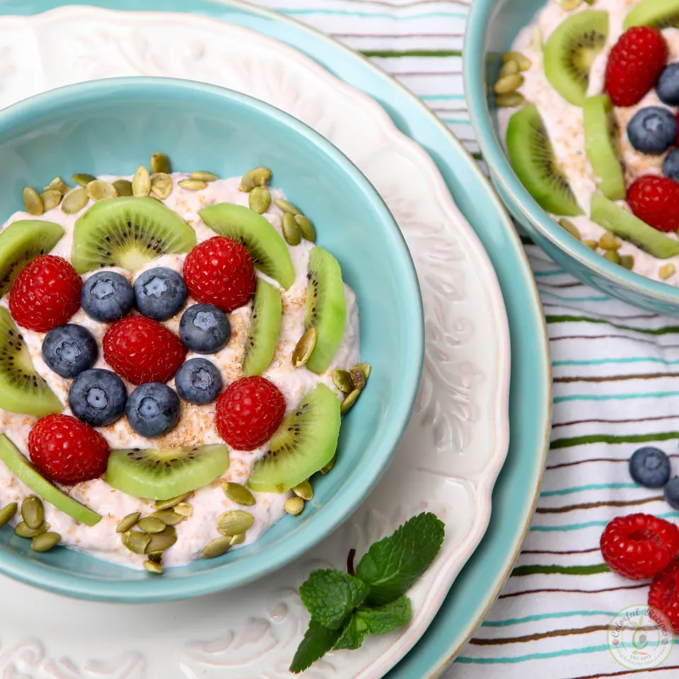 Banana yogurt breakfast bowl with raspberries, blueberries, kiwi and fresh mint