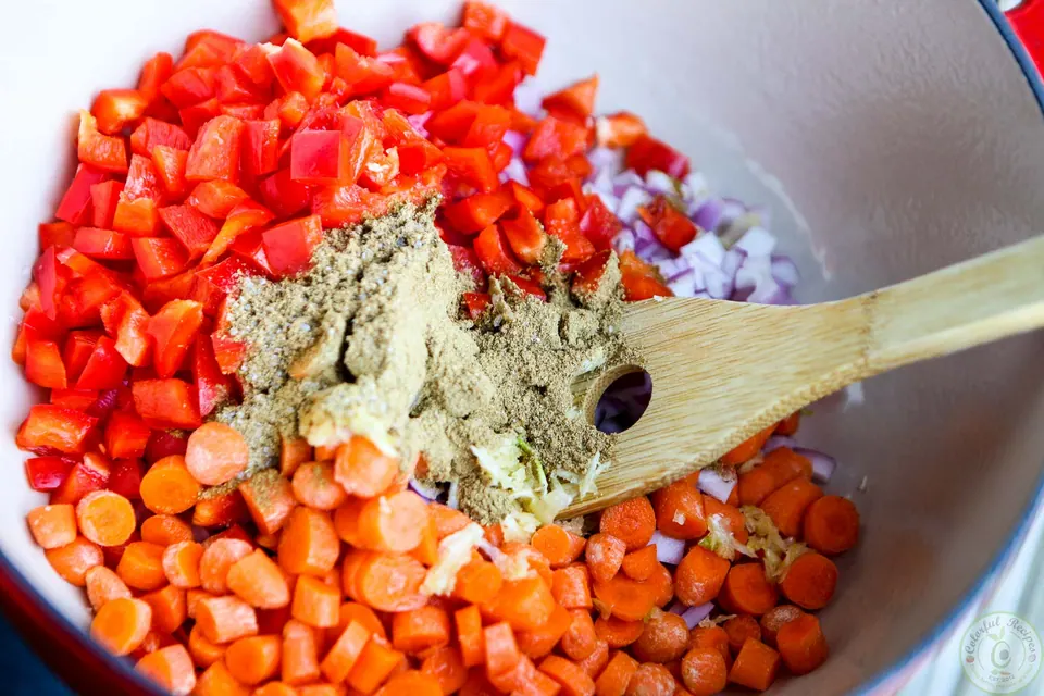 Chopped red bell pepper, carrots, onion and spices sautéing in a Dutch oven for lentil quinoa chili