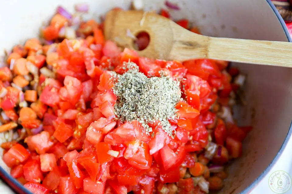 Chopped tomatoes and oregano added to the veggies in a Dutch oven for black bean chili