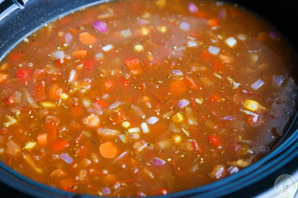 Uncooked black bean lentil quinoa chili with broth stirred together in a Crock Pot