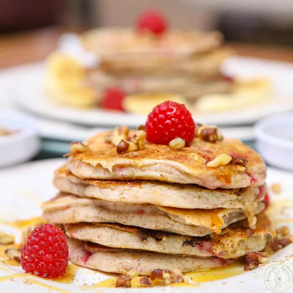 Close-up of a tall stack of vegan flax raspberry pancakes with walnuts and raspberries