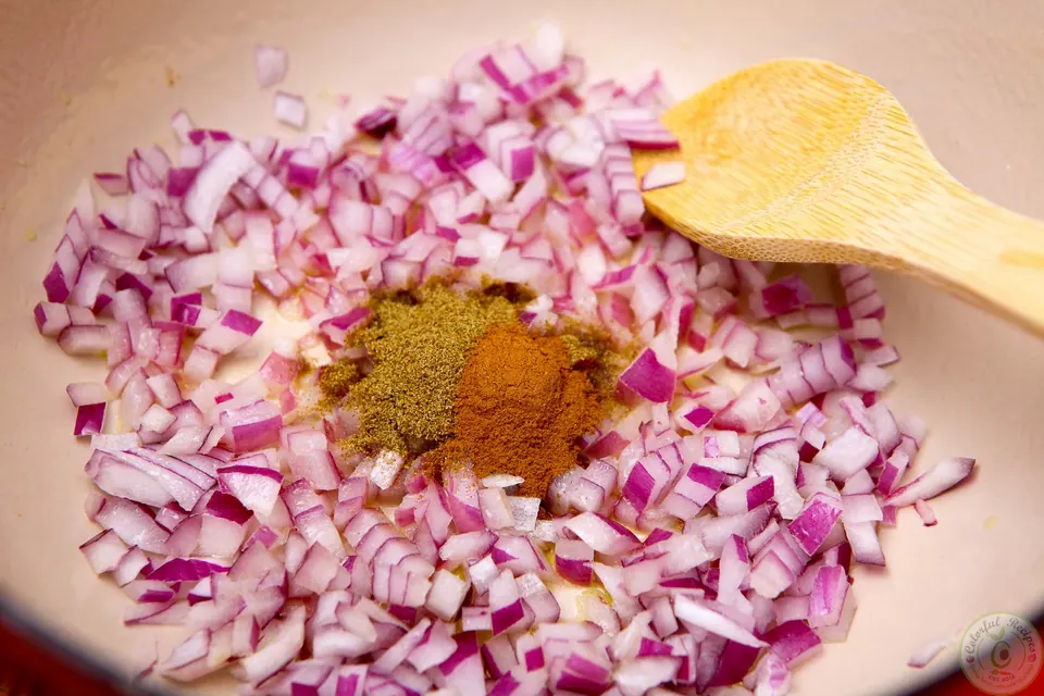 Chopped red onion with cumin and cinnamon in a Dutch oven for red lentil soup