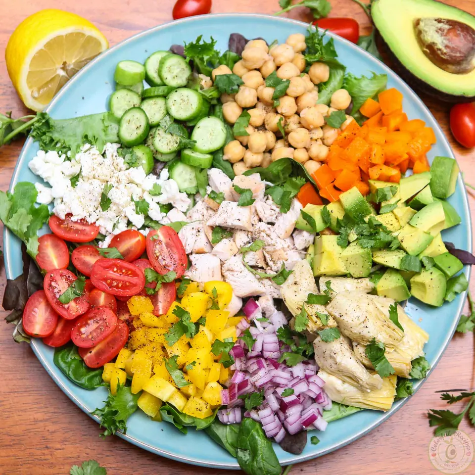 Colorful chopped salad platter with lemon, avocado and cherry tomatoes on the side