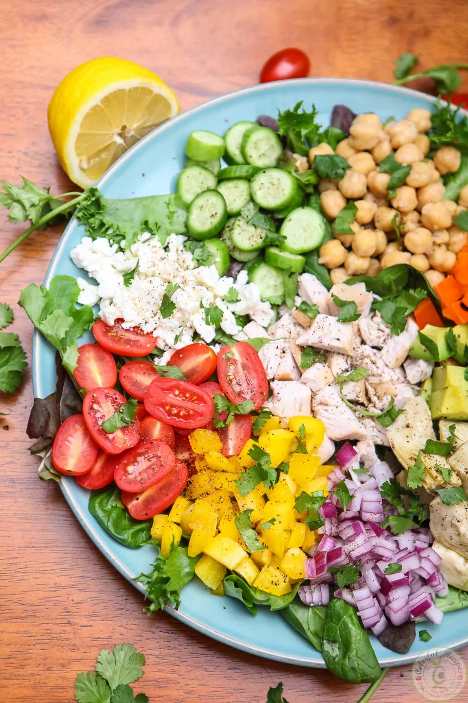 Fresh chopped salad arranged in sections with cucumbers, peppers, red onion and artichoke hearts