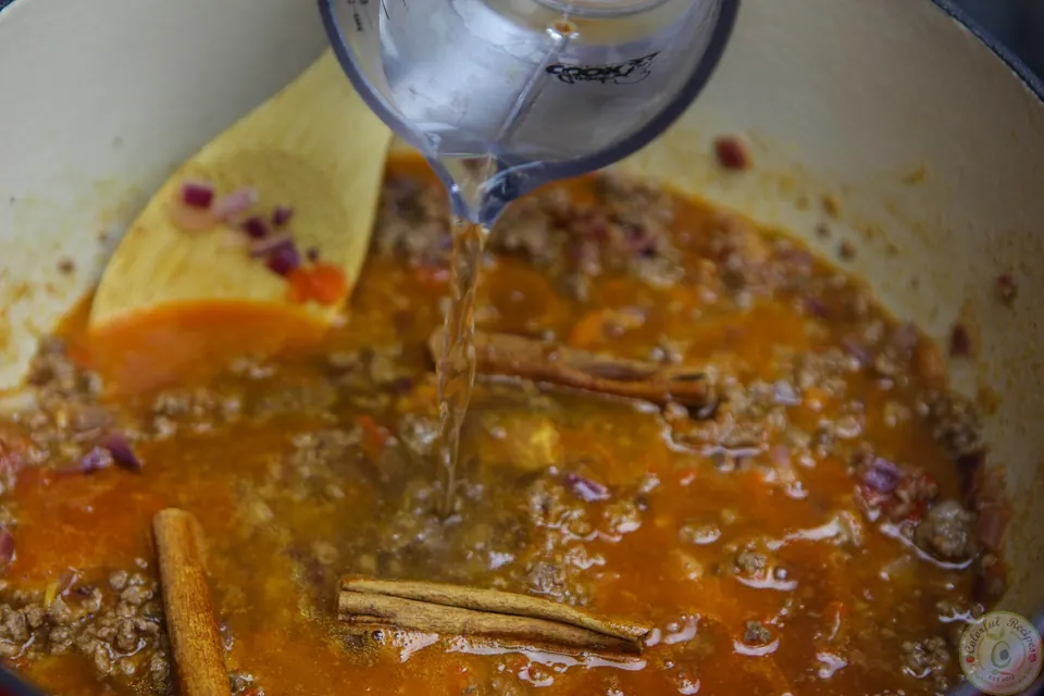 Beef tomato sauce with cinnamon sticks coming to a boil
