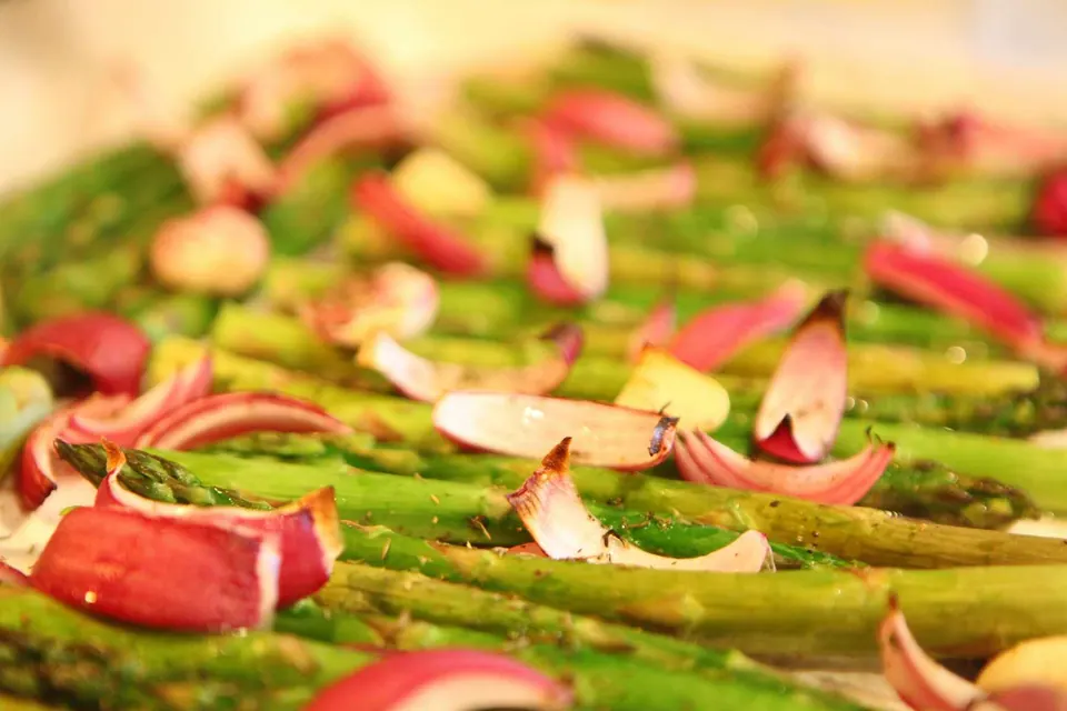 Smooth, bright green roasted asparagus creamy soup in a white bowl