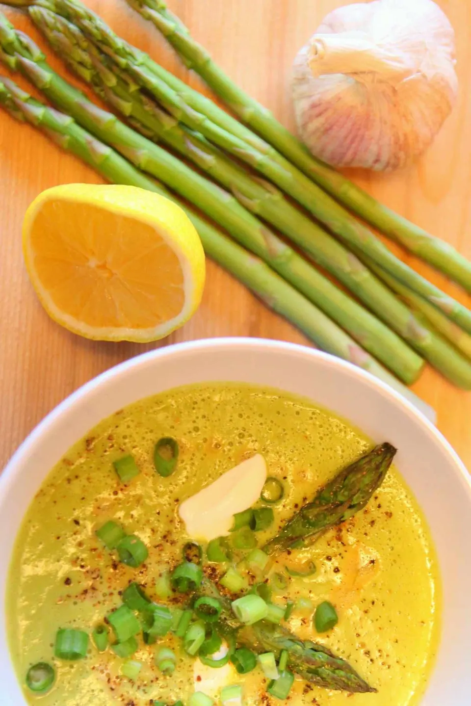 Bowl of roasted asparagus creamy soup topped with sour cream and asparagus tips