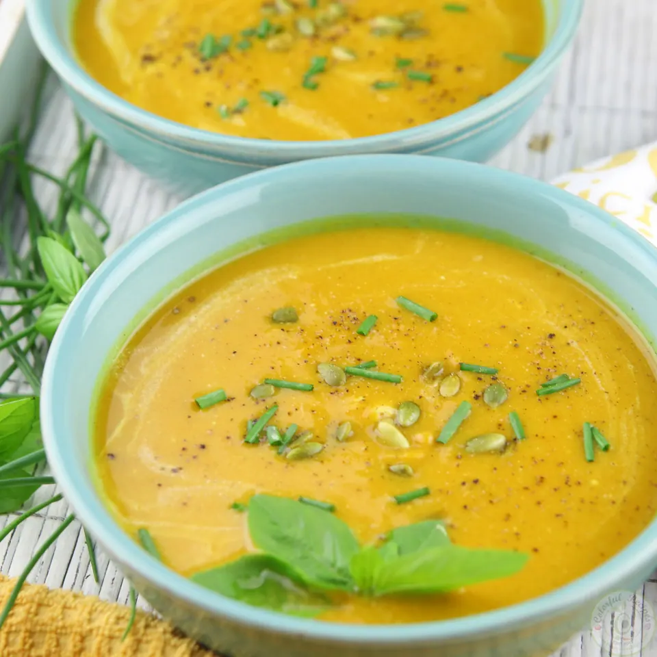 Bowls of butternut squash sweet potato soup with basil, green onions and black pepper