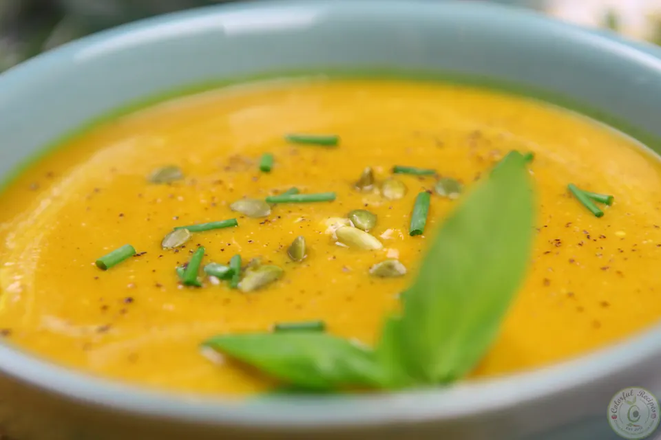 Close-up of creamy butternut squash sweet potato soup topped with fresh basil and green onions