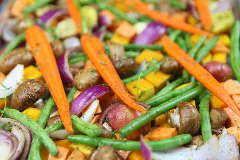 Roasted fall vegetables with carrots, green beans, butternut squash and mushrooms on a baking sheet