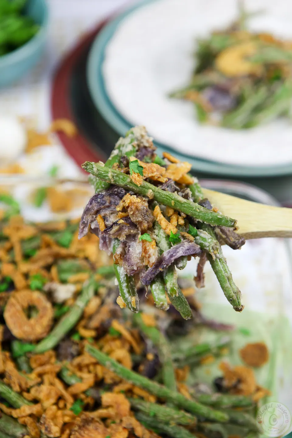 Forkful of cashew cream green bean casserole with crispy onions