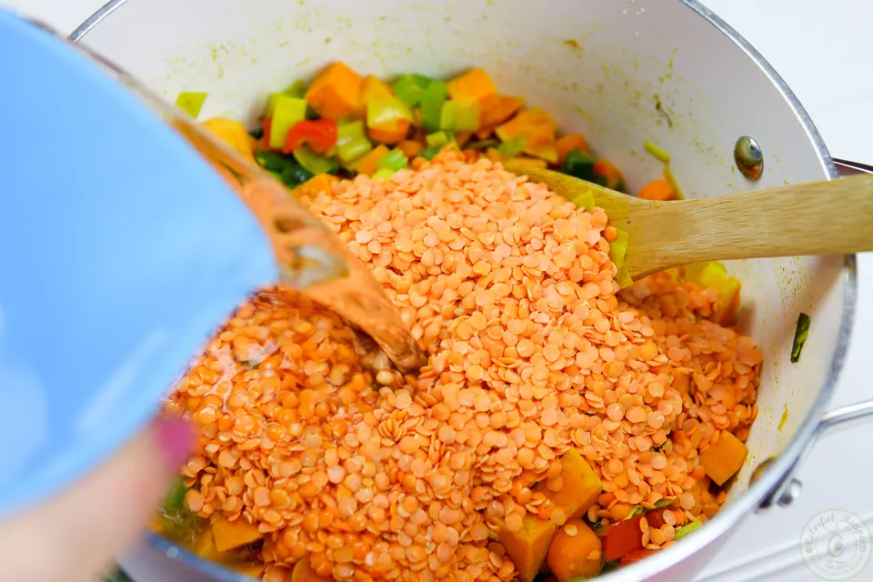 Vegetables cooking with cumin and turmeric in a soup pot