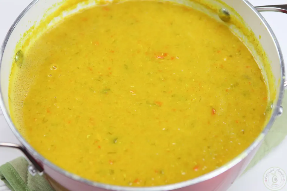 Hand blender pureeing red lentil veggie soup in the pot