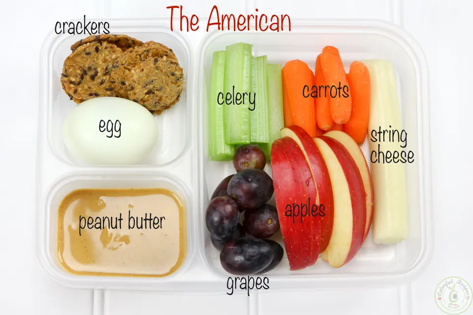 The American protein bento box with peanut butter, egg, crackers, celery, carrots, string cheese, grapes and apples